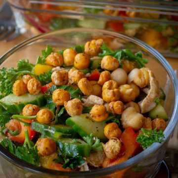 Mediterranean salad topped with roasted chickpeas in a glass bowl.