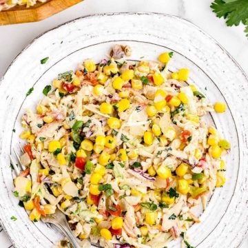 Coleslaw topped with corn, peppers and herbs.