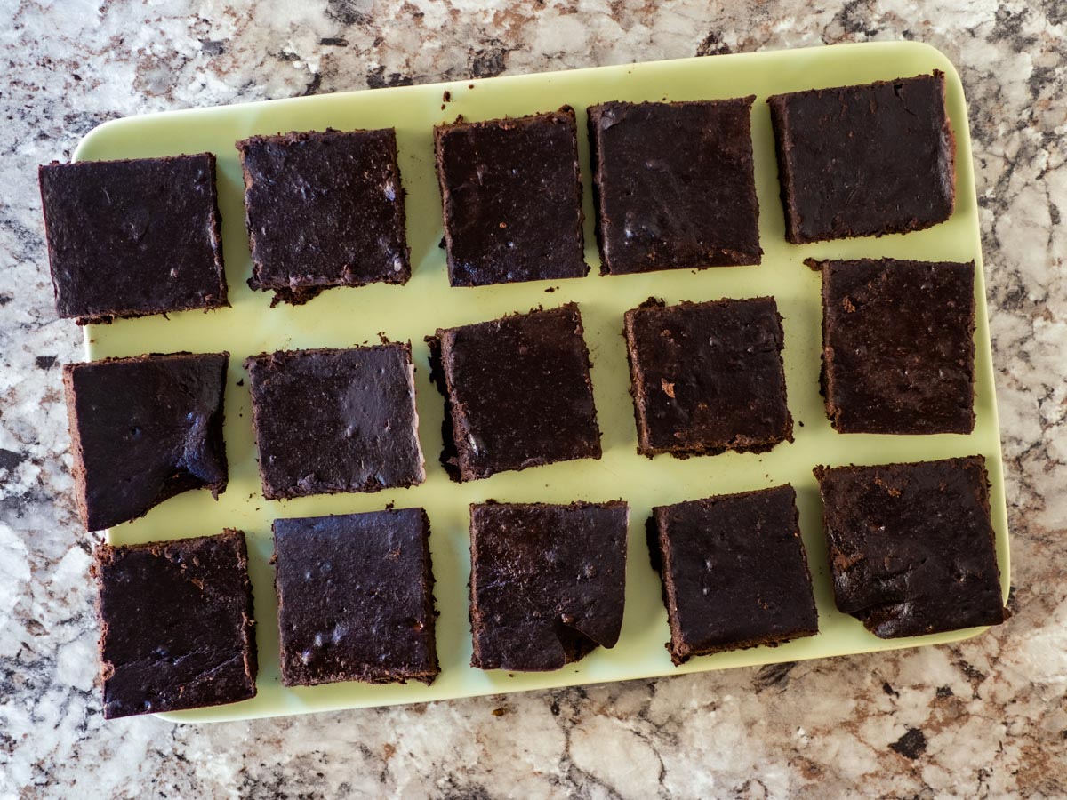 Top view of 15 brownie squares assembled on a green plate.