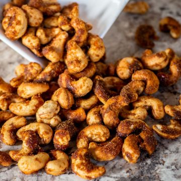 Honey roasted cashews being poured out of a bowl.