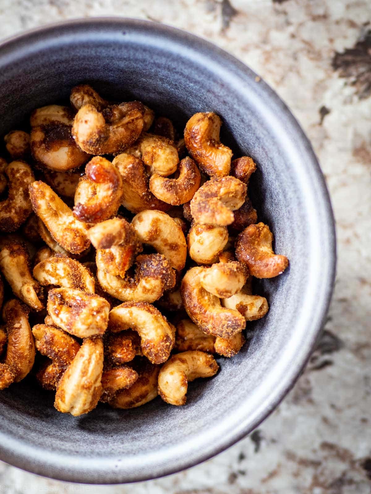A grey stone bowl filled with honey roasted cashews.