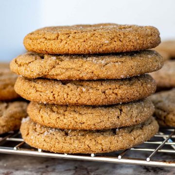 Stack of gingersnaps made with oat flour sitting on a wire rack.