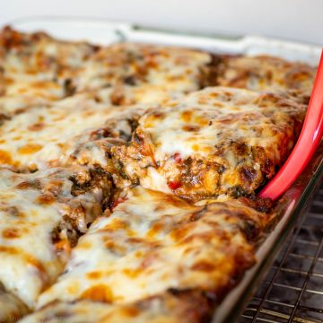 Spatula lifting a piece of lasagna from a casserole dish.