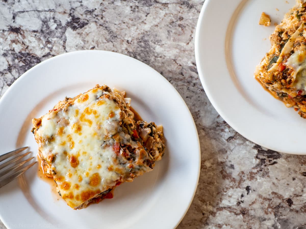 White plate with a piece of lasagna and a fork.