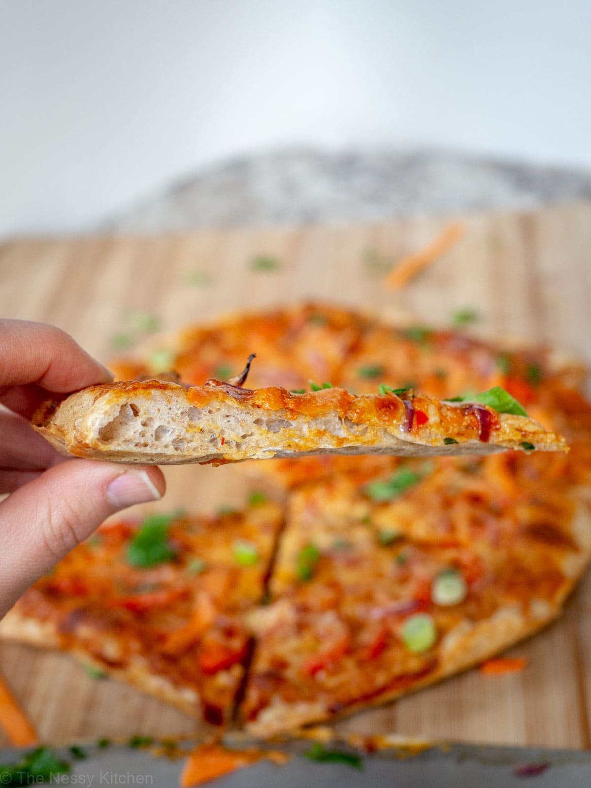 Slice of Thai curry pizza on homemade whole wheat artisan pizza crust.