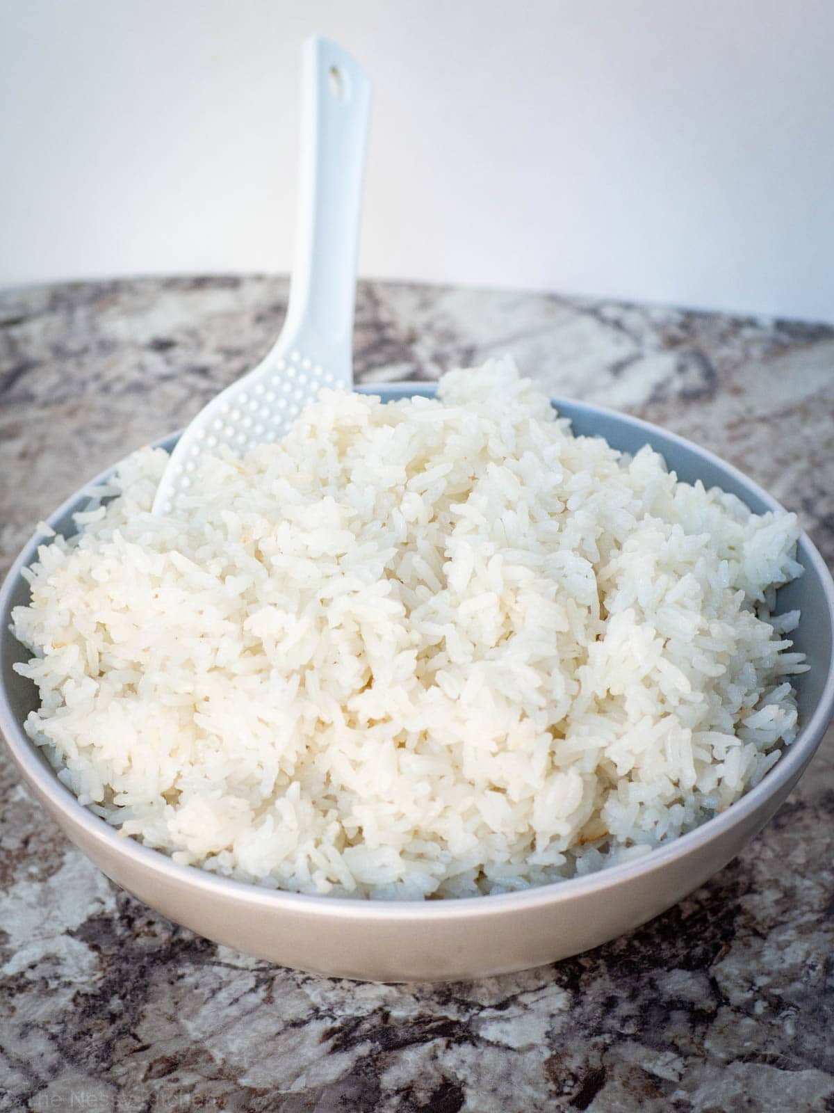 Coconut rice in a grey bowl with a white spoon.