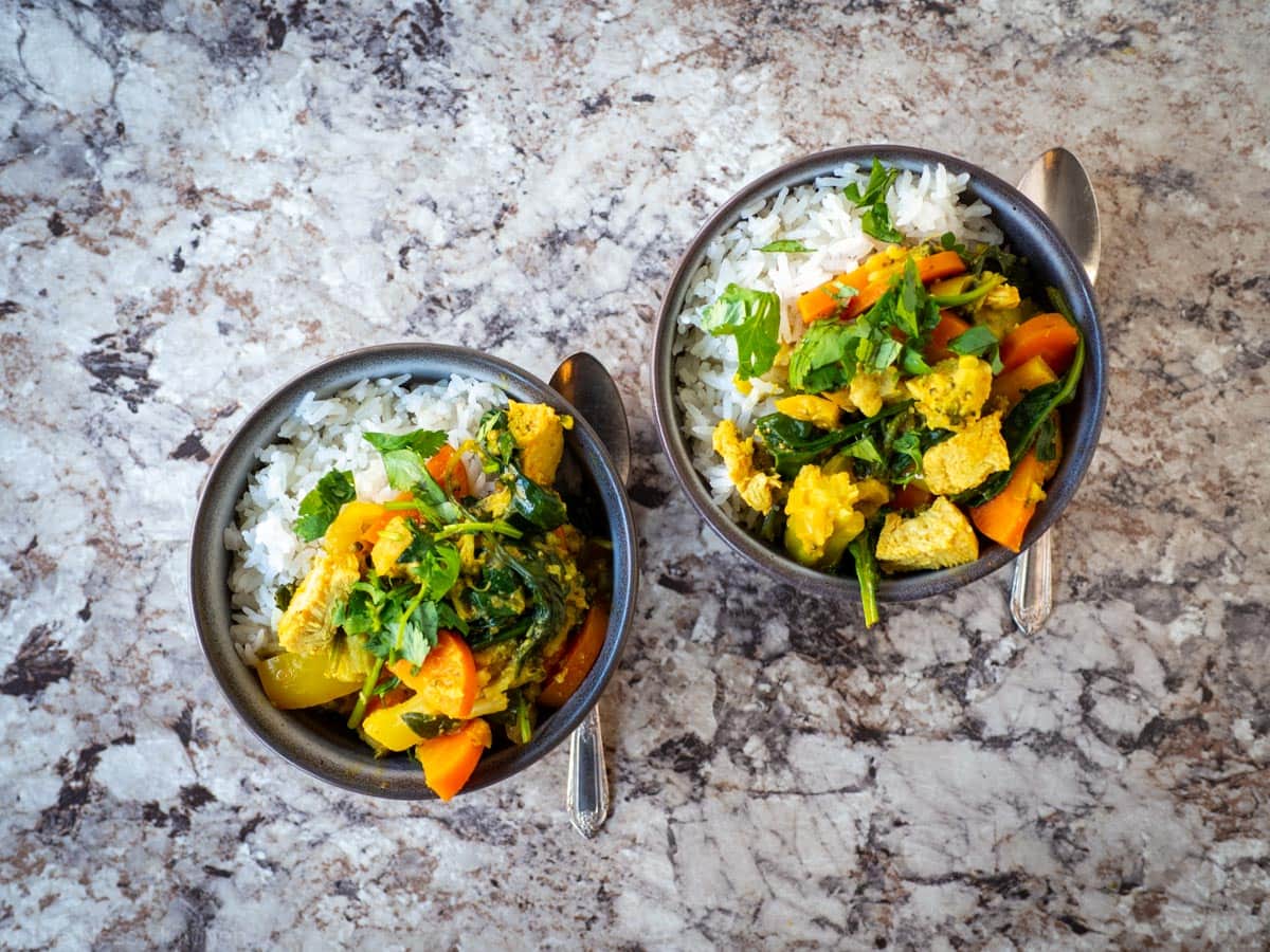 Top view of two bowls of Thai curry with coconut rice.