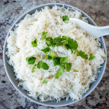 Top view of a bowl of rice cooker coconut rice that has been garnished with cilantro.