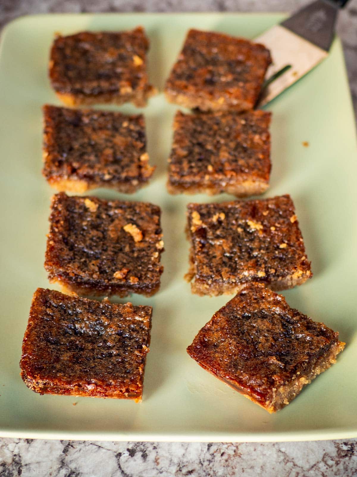 Butter tart squares on a green plate.