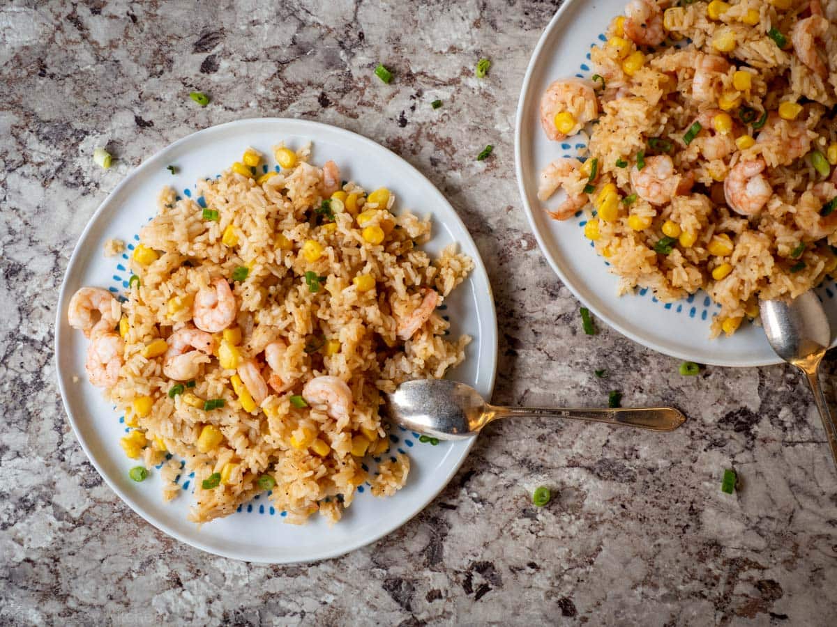 Shrimp, rice and corn combined on a blue and white plate.