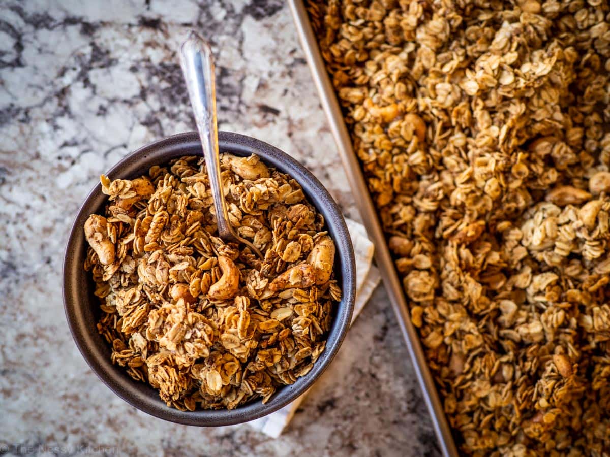 Grey bowl of granola next to a sheet pan.