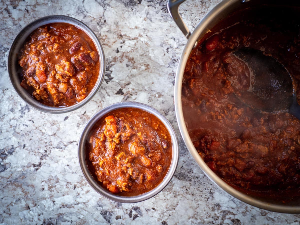 Chili being ladled out into two bowls.