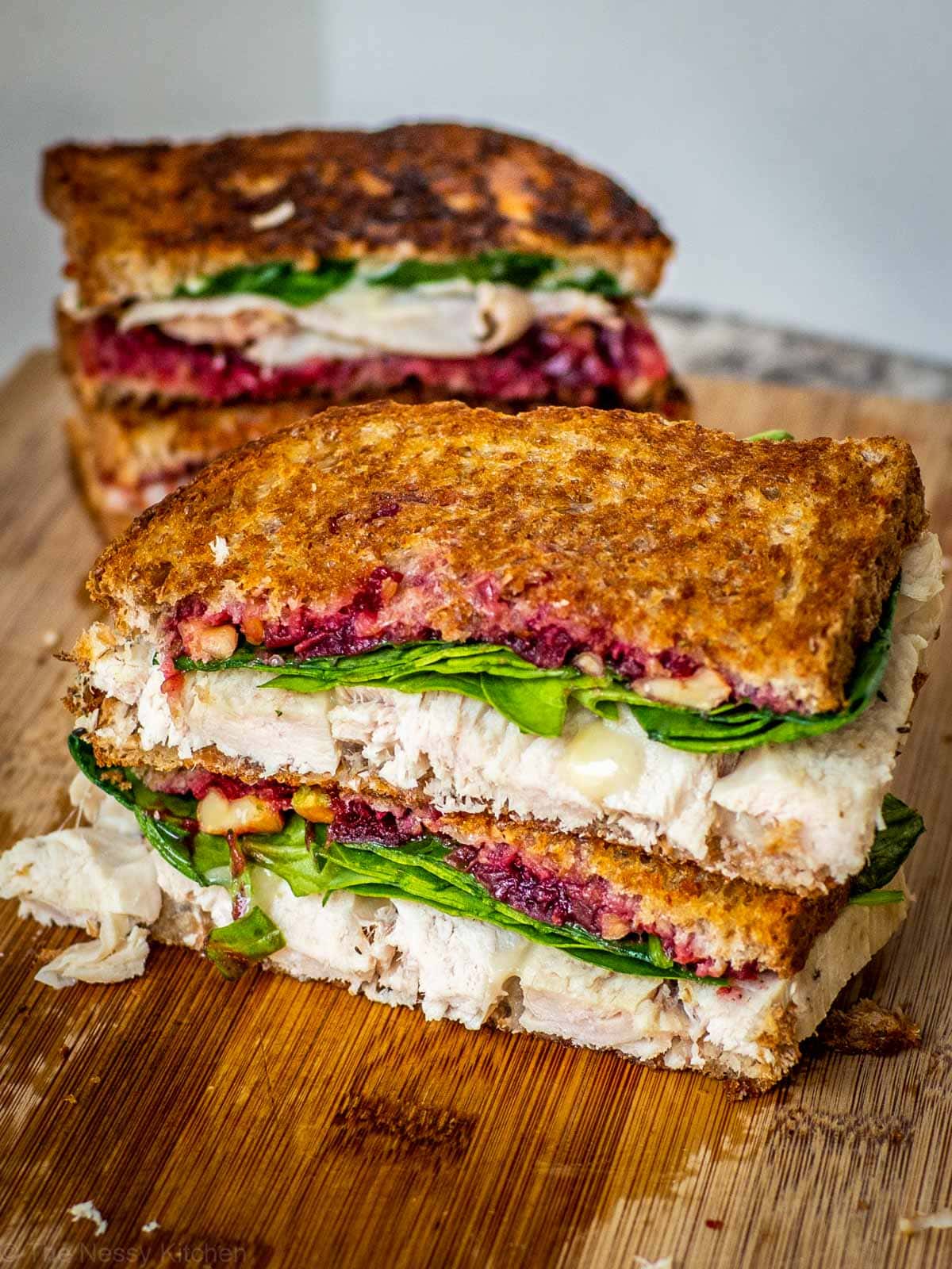 Close up shot of a cranberry brie and turkey sandwich that has been sliced in half.