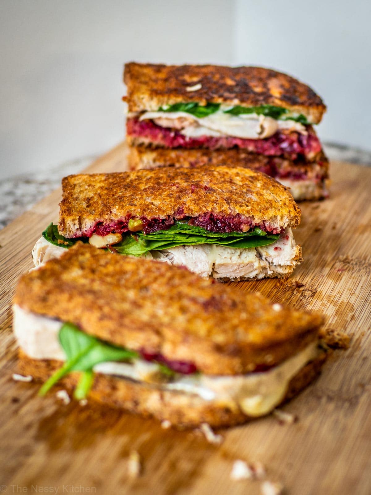 Cranberry turkey sandwich on a wooden cutting board.