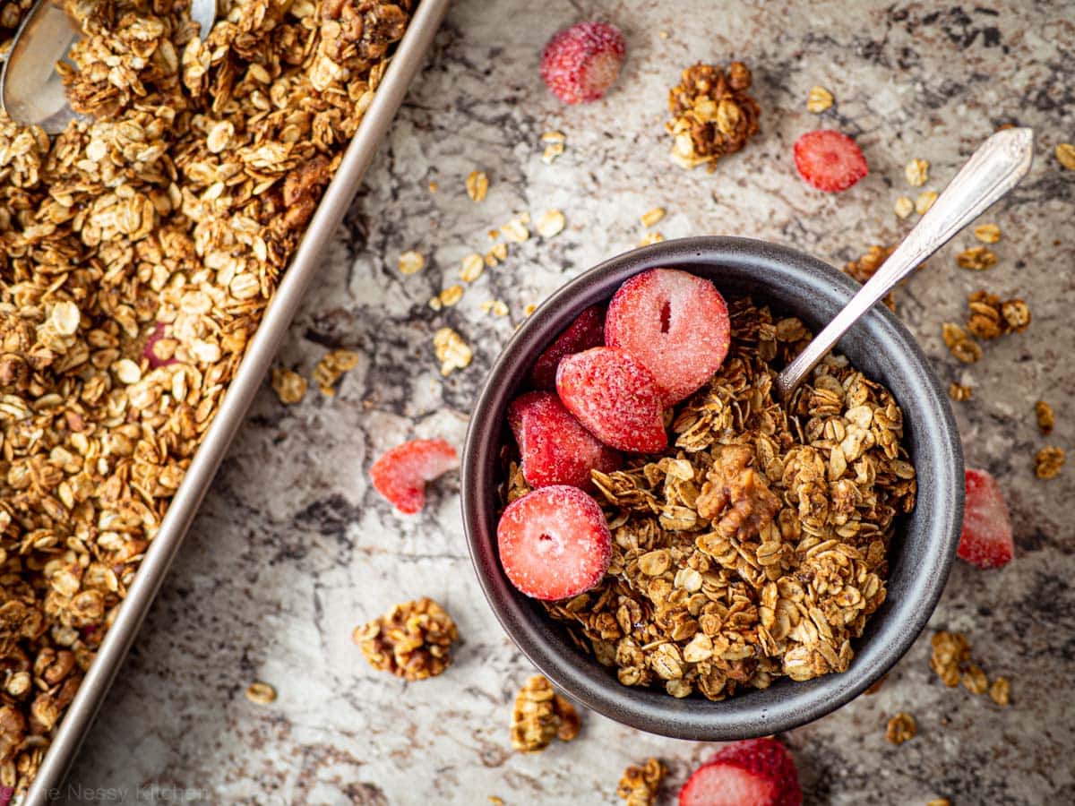 Granola in a grey bowl topped with sliced strawberries.