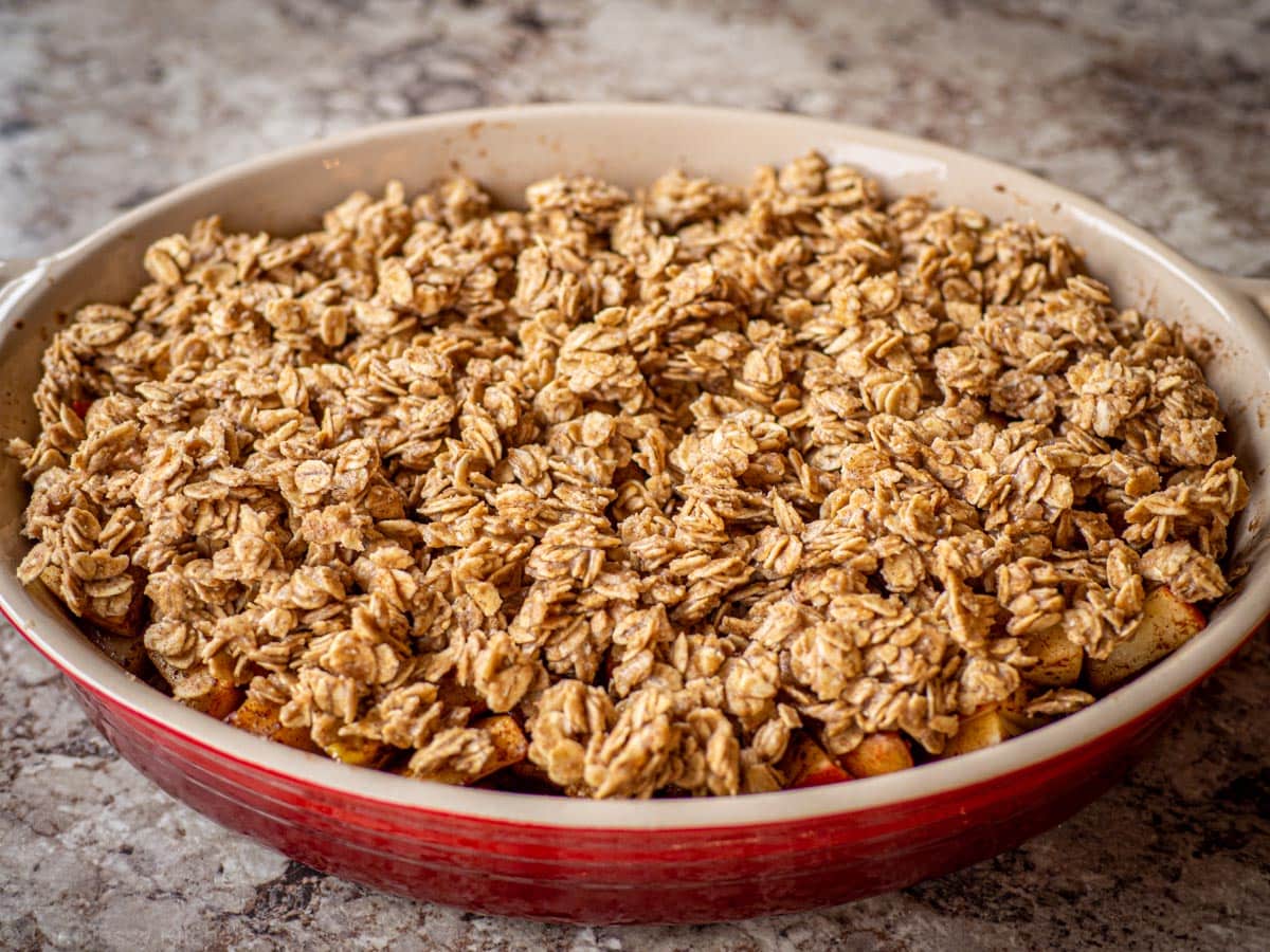 Oat crisp topping placed on top of a layer of apples.