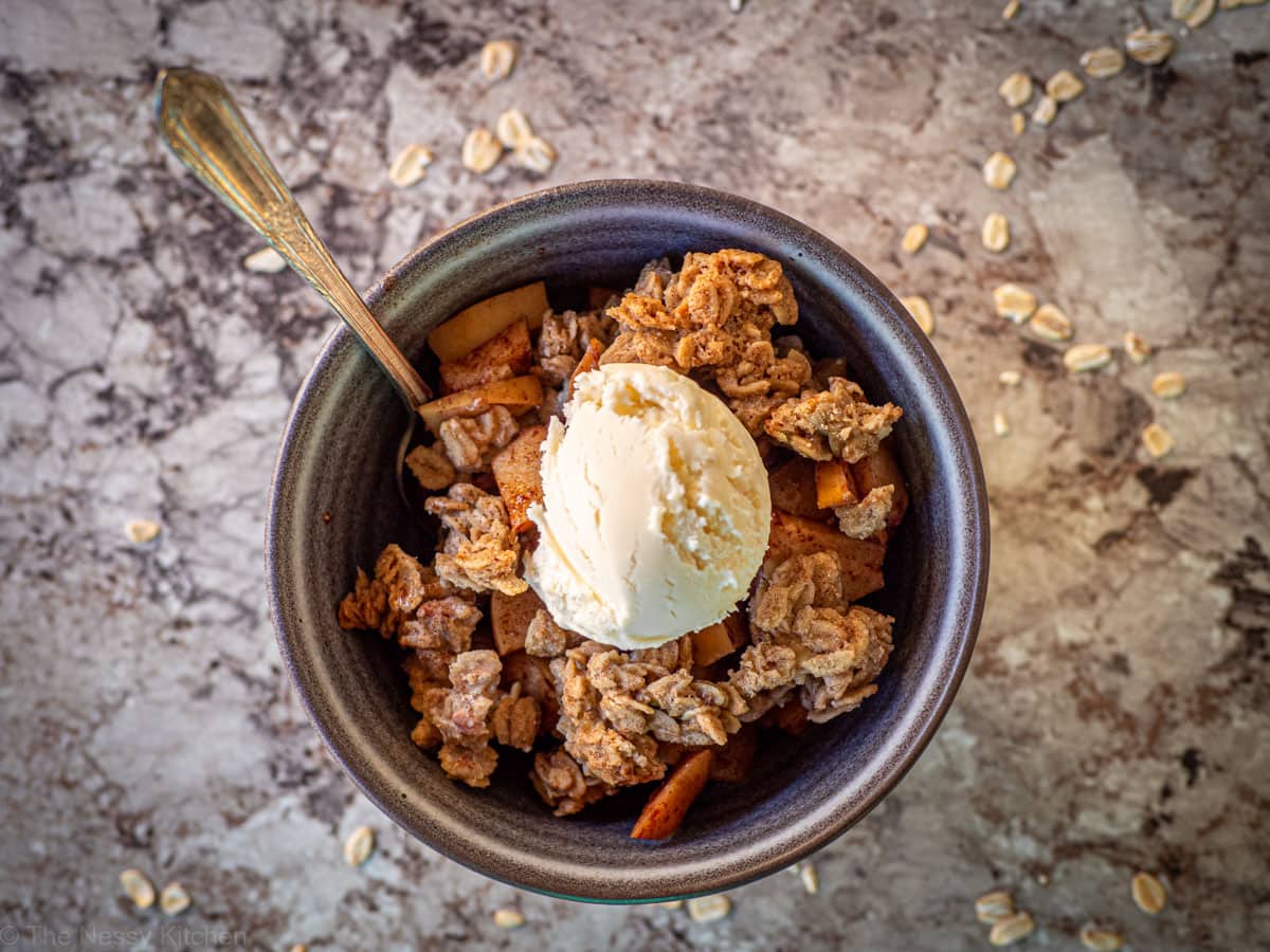 Bowl of apple crisp topped with ice cream.