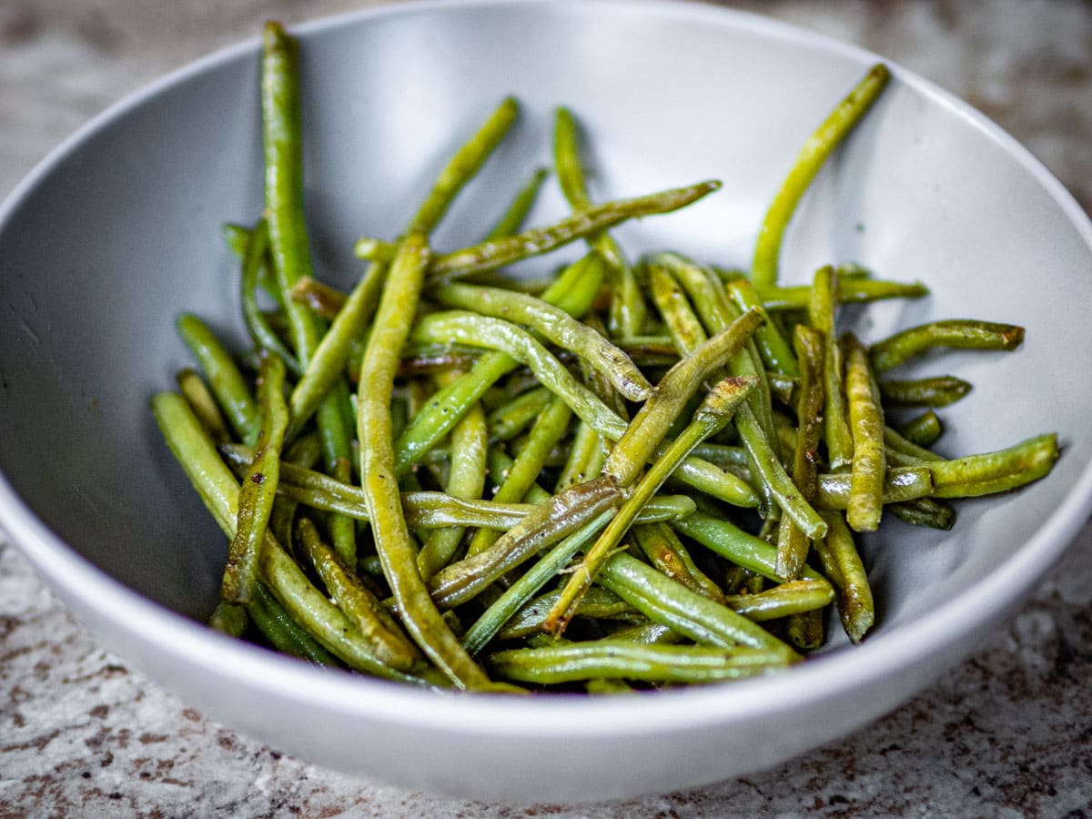 Sautéed frozen green beans in a grey bowl.