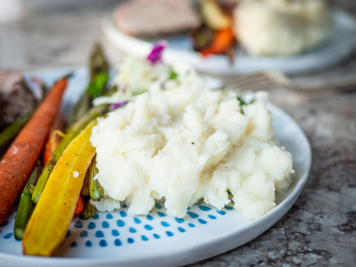 Mashed potatoes on a plate with asparagus, carrots and pork.