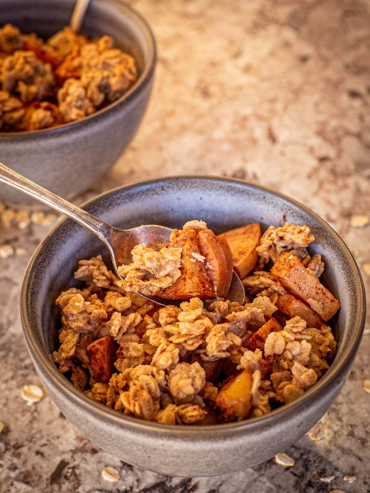 Spoonful of apple crisp in a bowl.