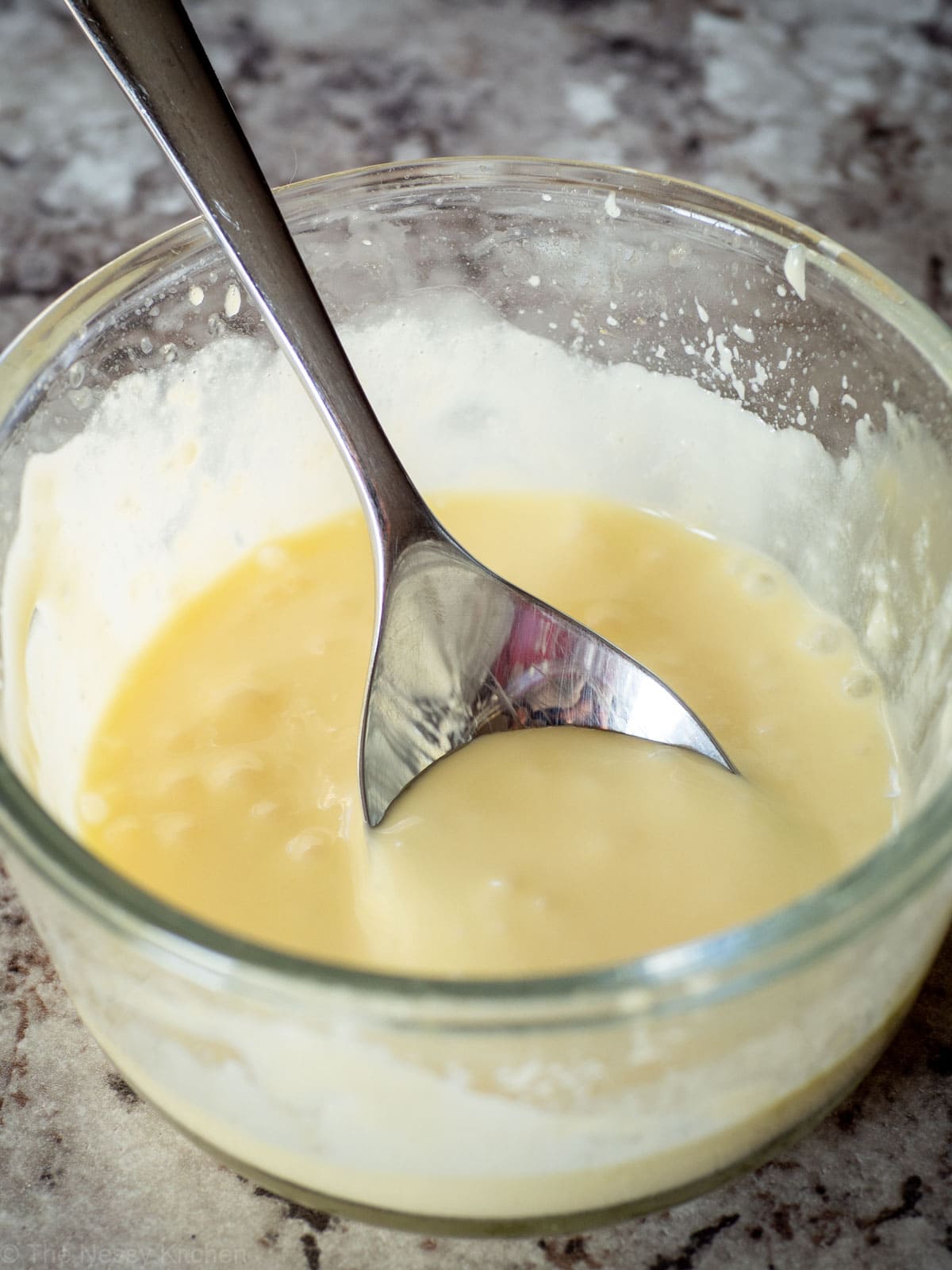 Small dish of Hollandaise sauce with a spoon in it.