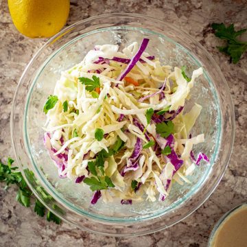 Lemon tahini slaw in a glass serving bowl.