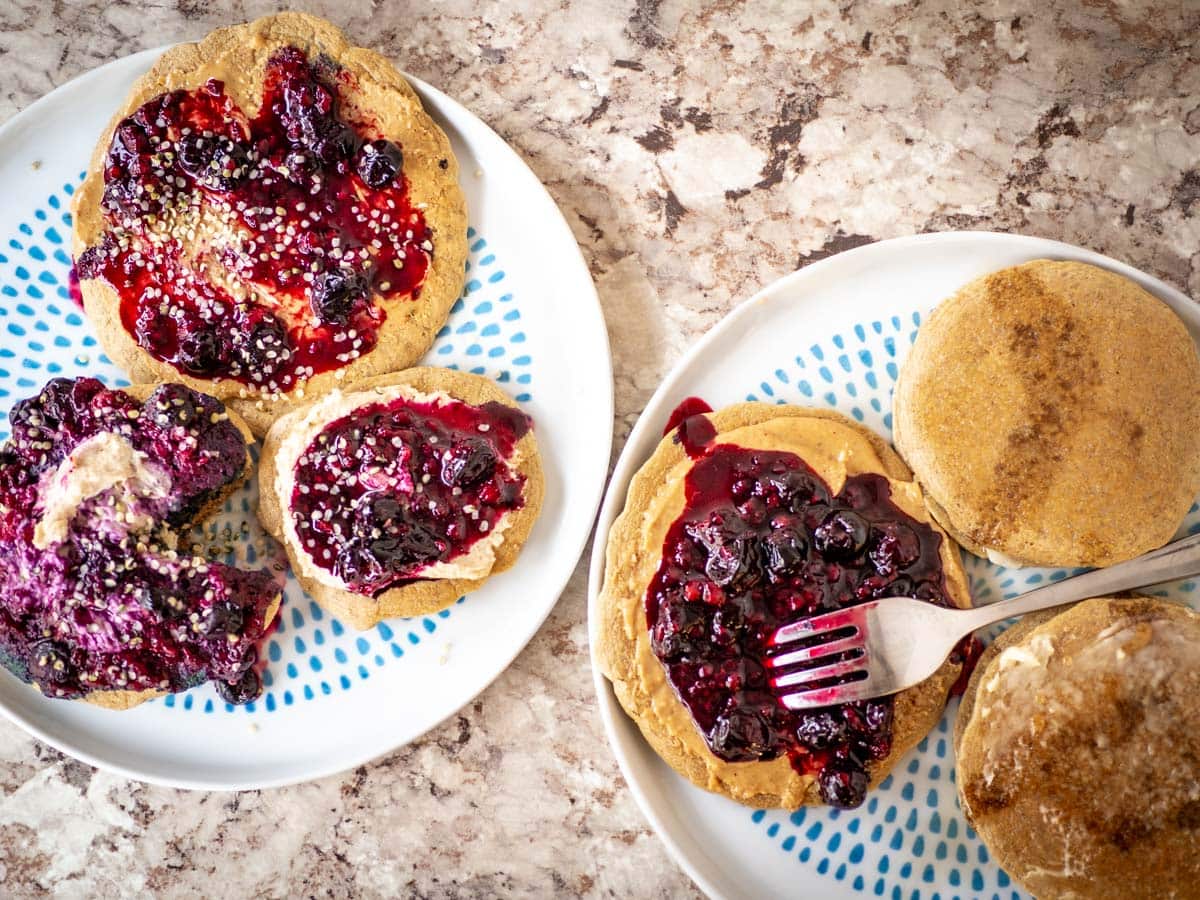 Top view of two plates of pancakes loaded with various toppings.