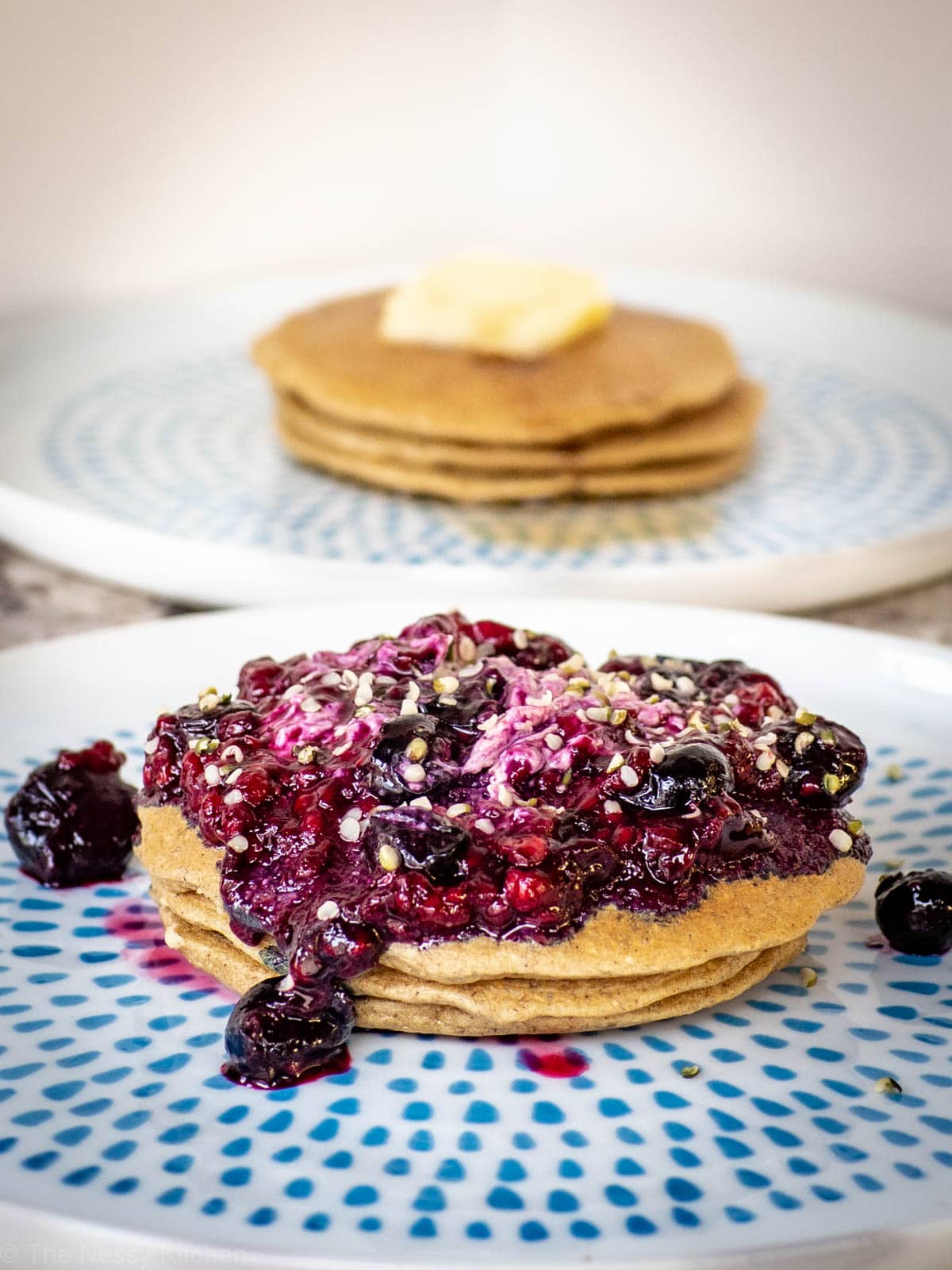 Plate of pancakes topped with yogurt, berries and hemp seeds.