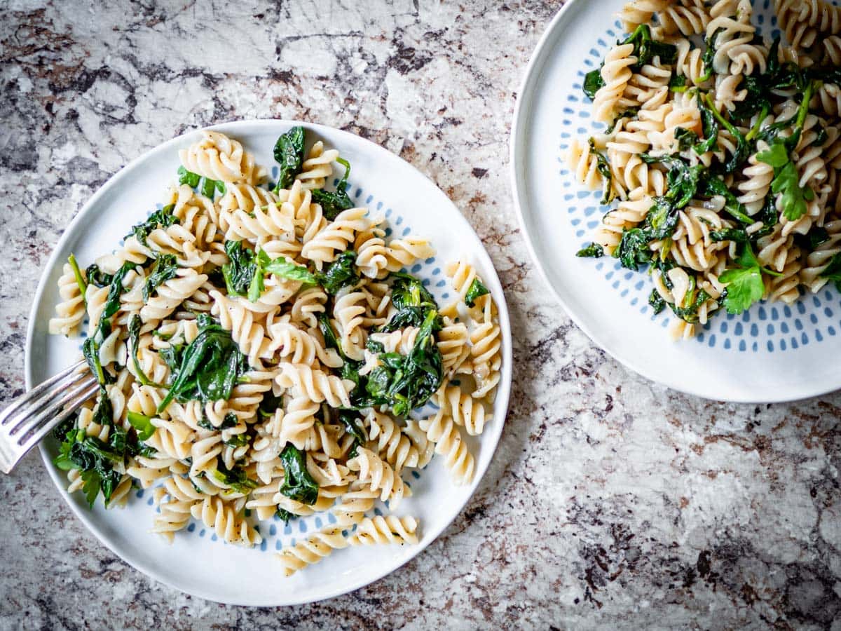 Top view of two plates of spinach pasta.