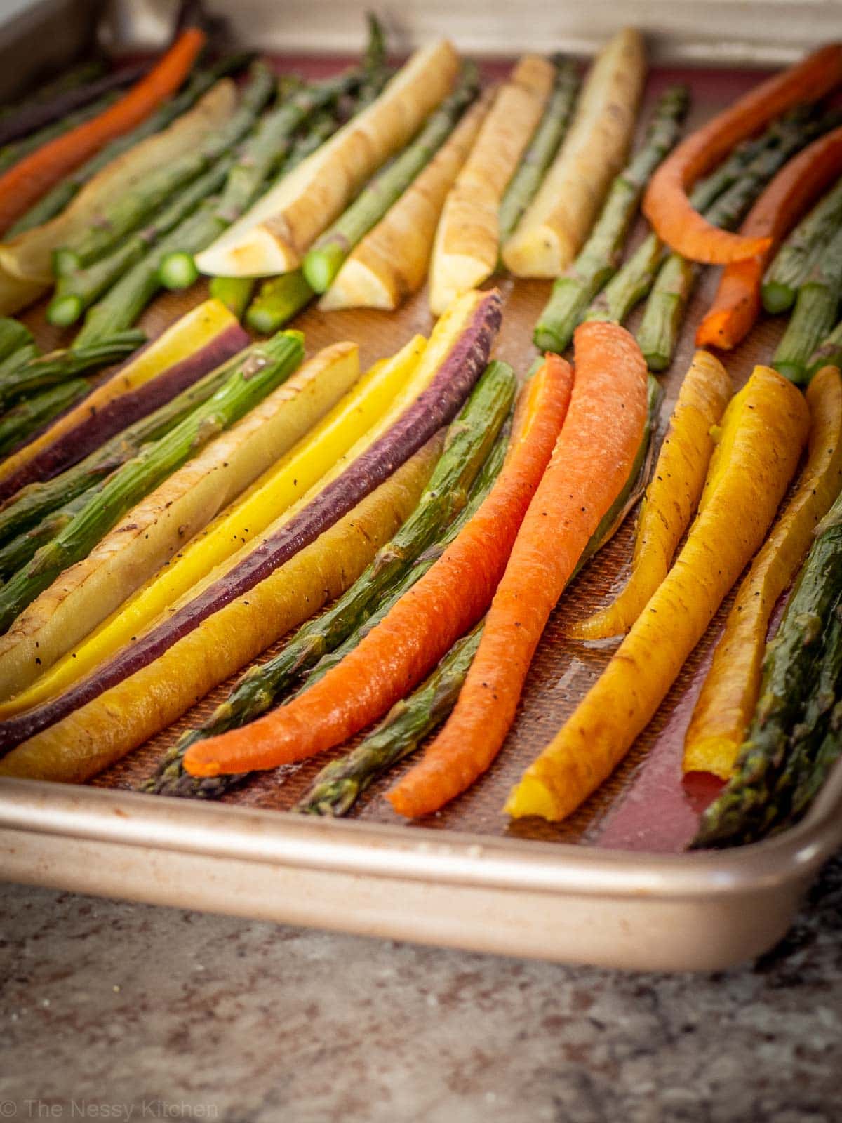 Multi colored carrots and asparagus on a sheet pan.