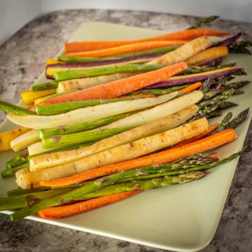 Roasted carrots and asparagus on a green plate.