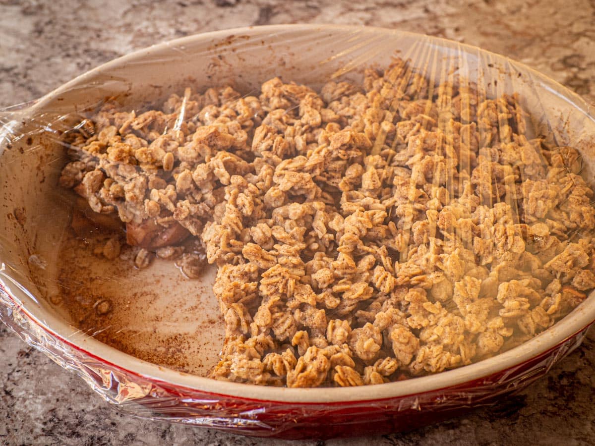 Apple crisp covered with plastic wrap.