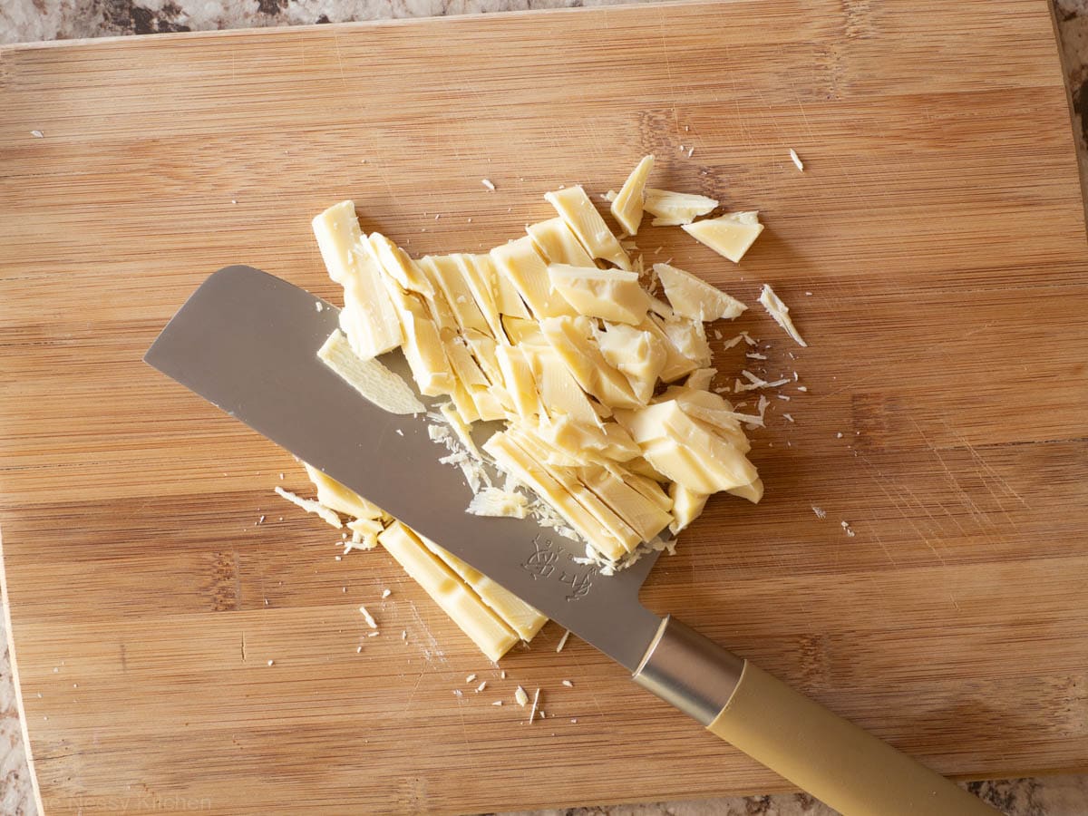 White chocolate chopped on a wooden cutting board.