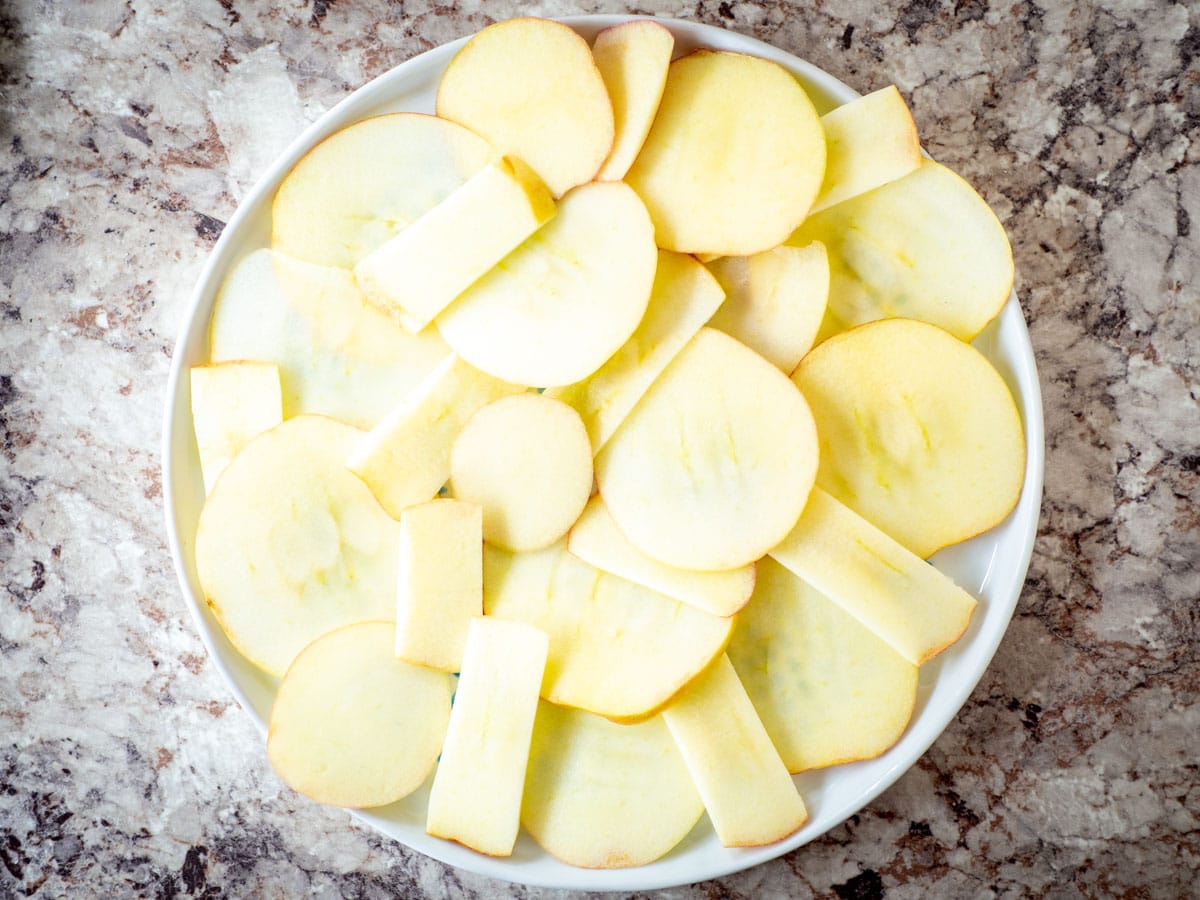 Sliced apples placed in a single layer on a plate.