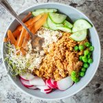 Canned salmon and rice topped with vegetables in a bowl with a spoon.