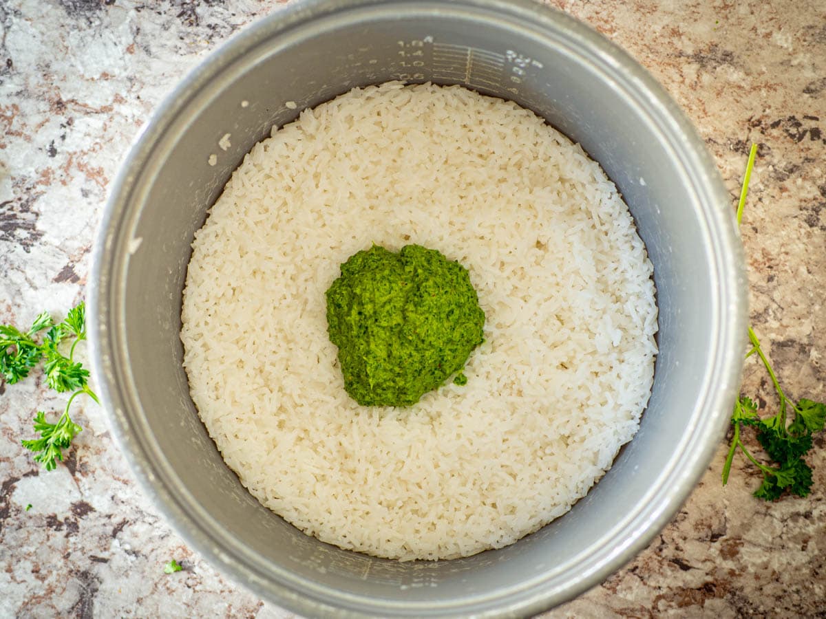 Cooked rice in a pot with Chimichurri spooned on top.