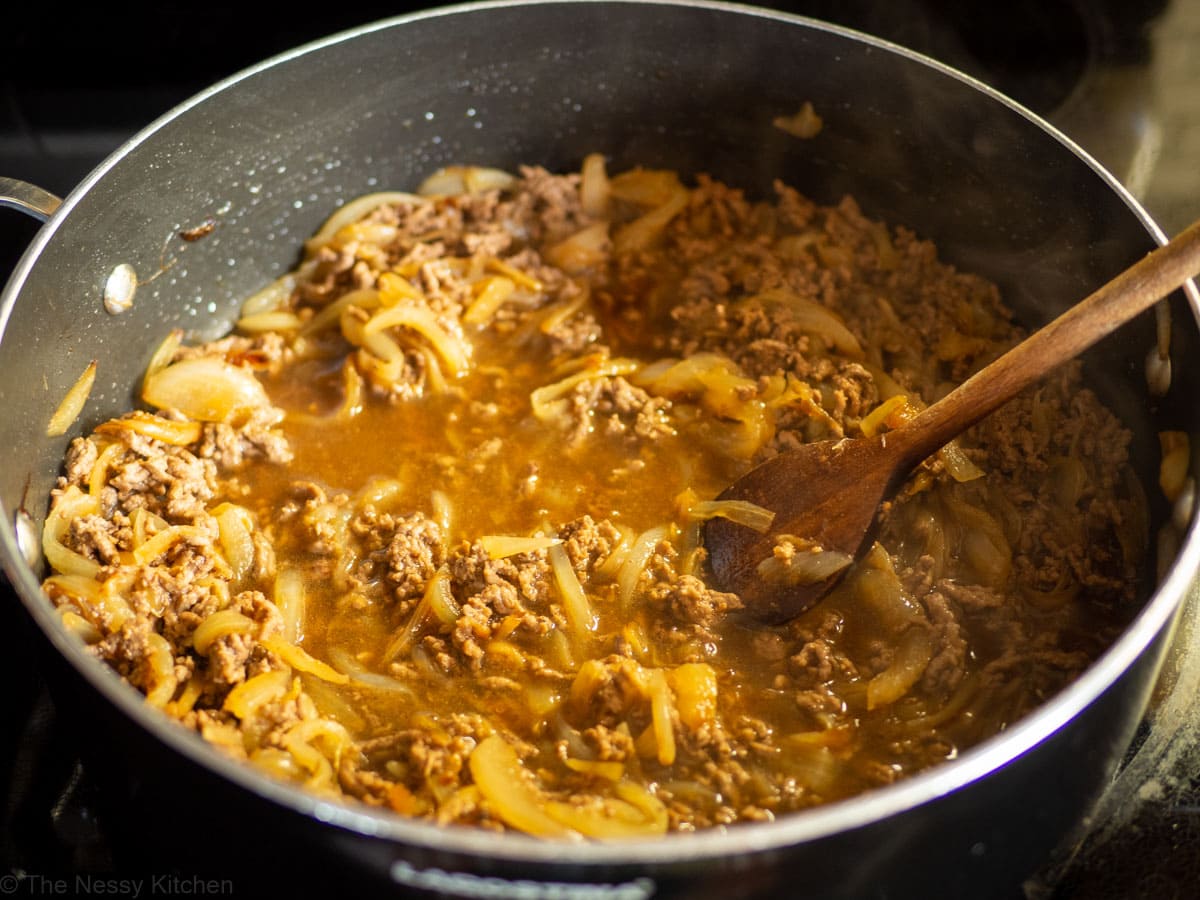 Ground beef and onions cooked in a sauce in a skillet.