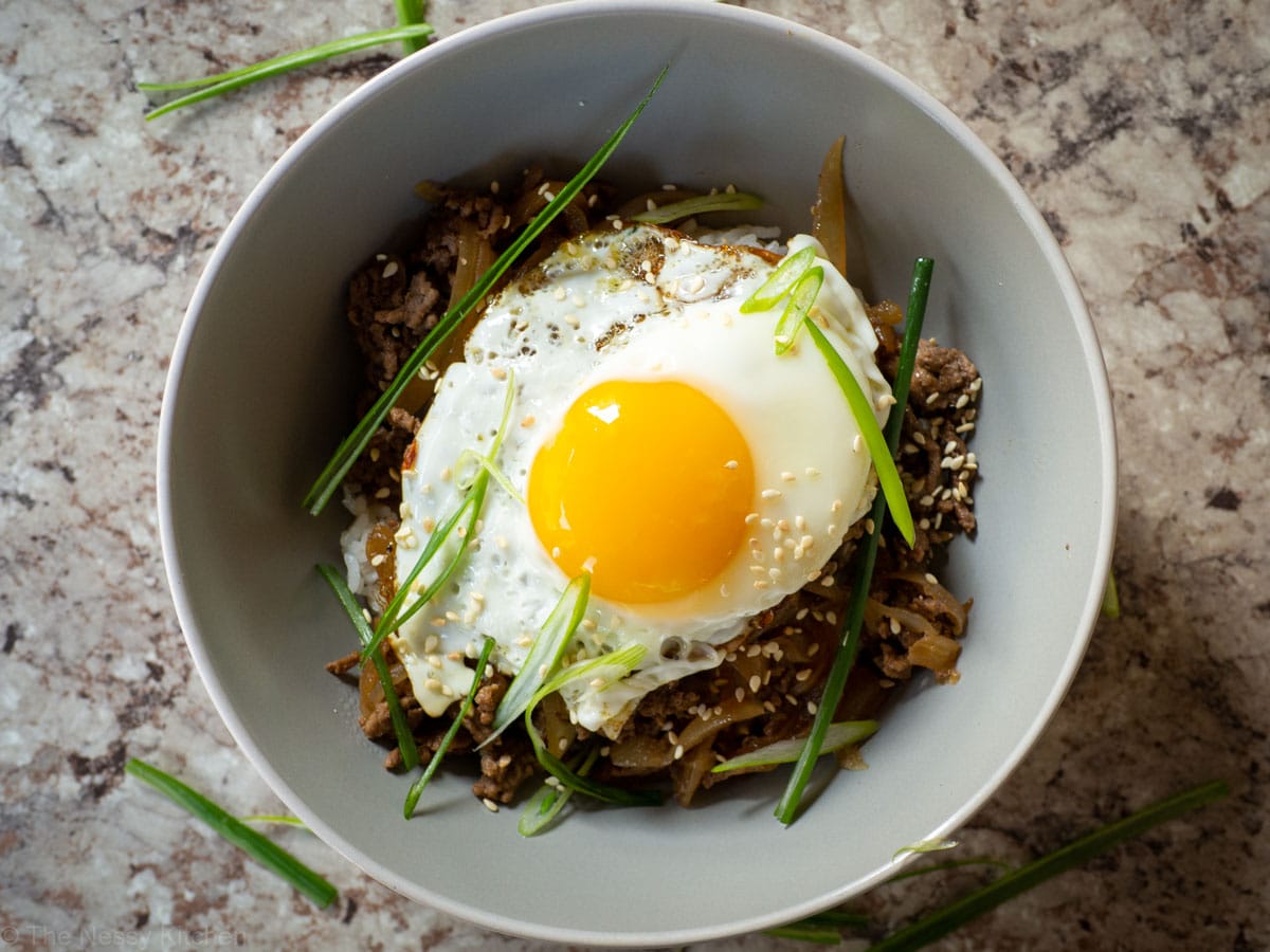 Bowl of rice topped with ground beef mixture and a sunny-side up egg.