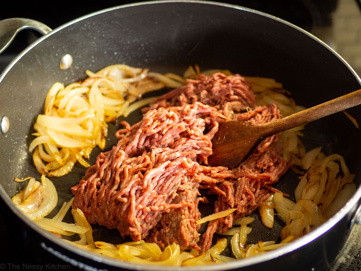 Ground beef added to the skillet with the onions to brown.