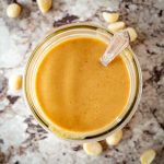 Top view of a jar of macadamia nut butter with a spoon.