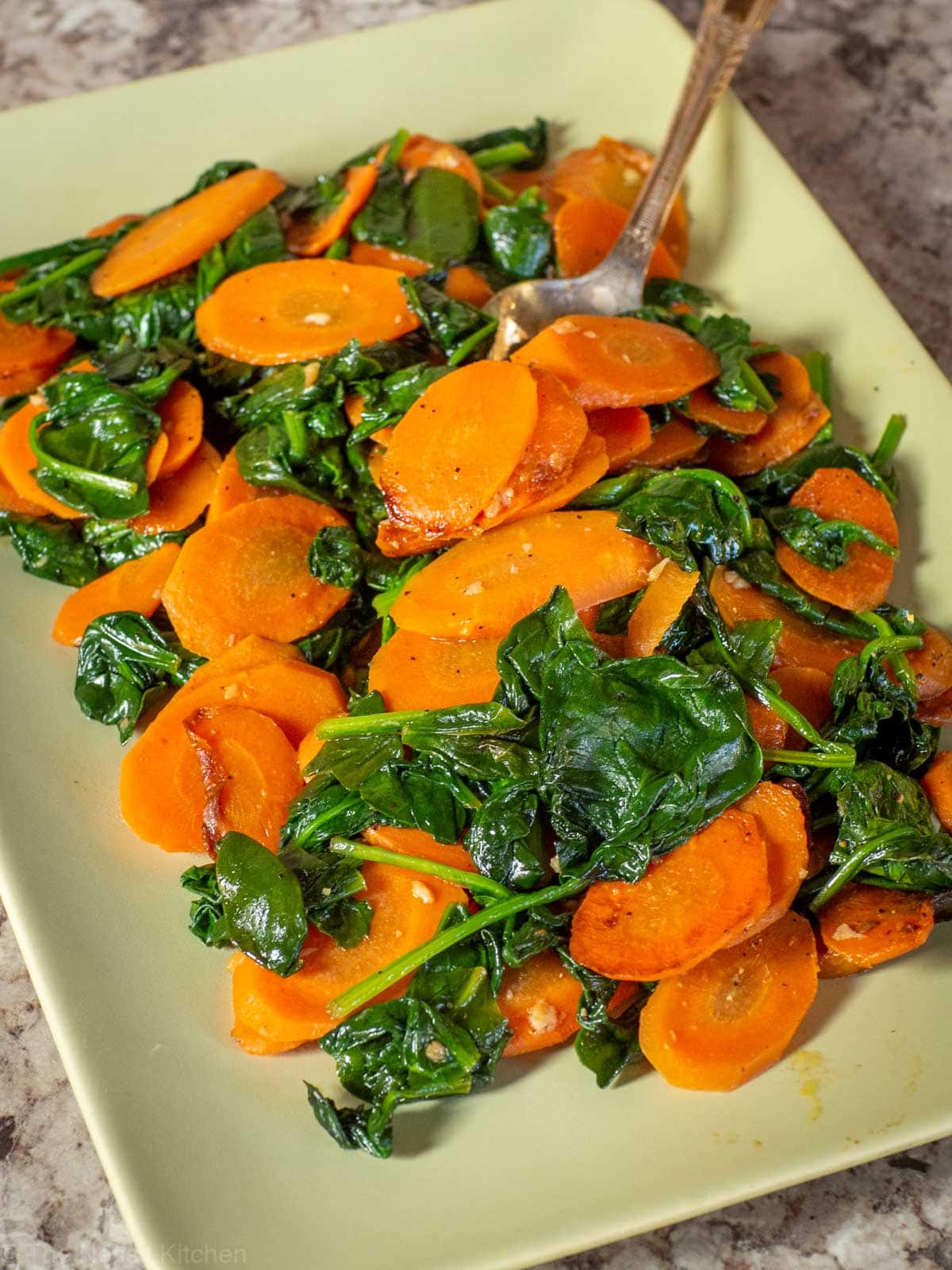 Carrots and spinach on a green dish.