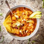 Bowl of slow cooker buffalo chili topped with tortilla chips and avocado.