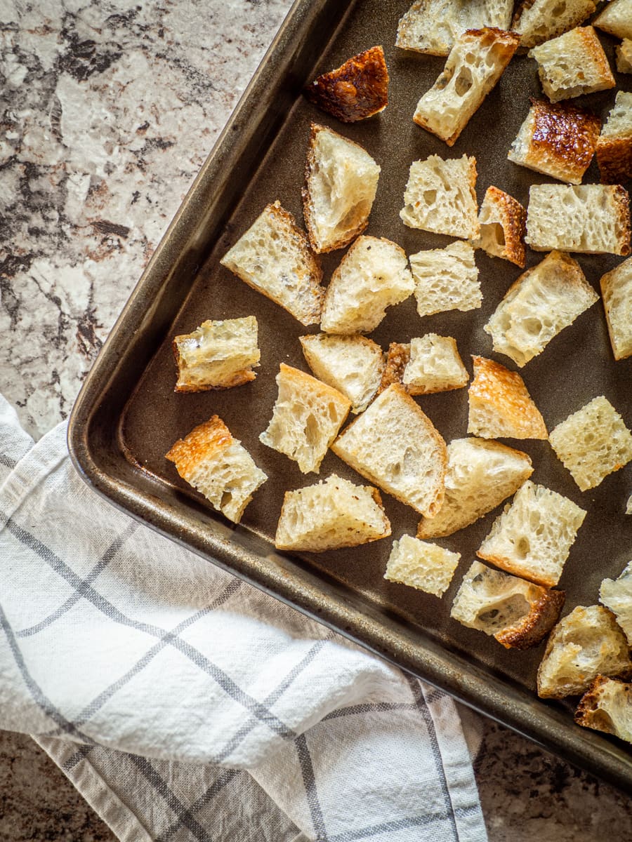Sheet pan of baked croutons next to a cloth napkin.