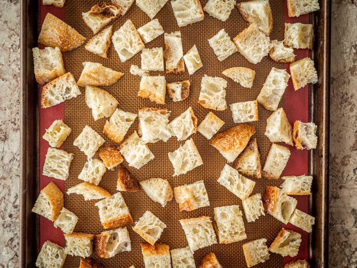 Bread cubes spread out on a baking sheet.