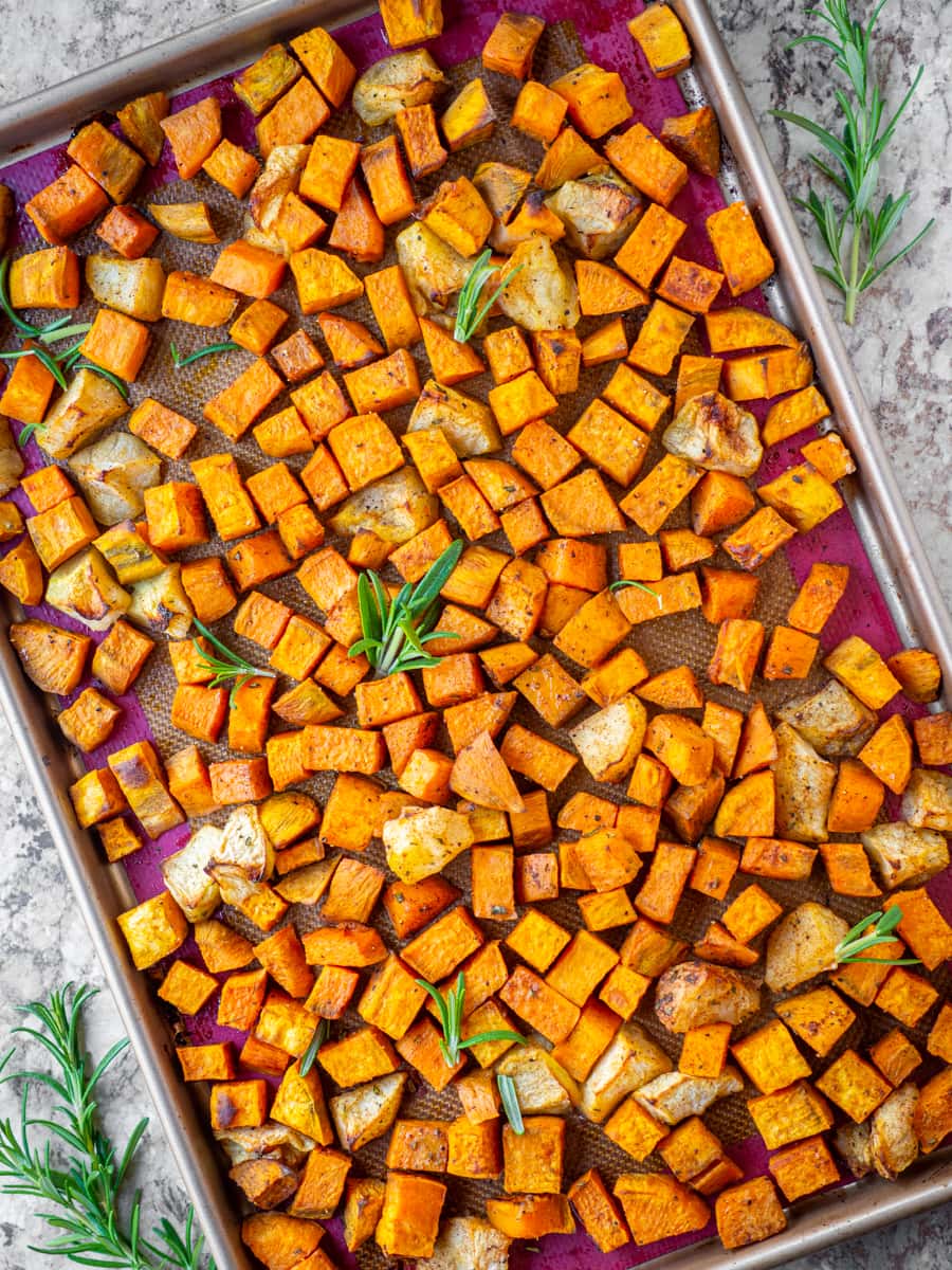 Sheet pan of apples and sweet potatoes topped with rosemary.