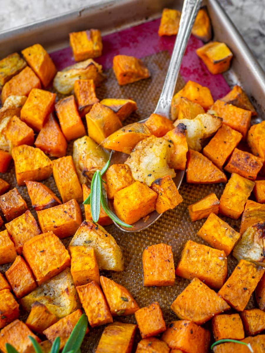 Serving spoon scooping a bite of baked sweet potatoes with apples.