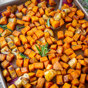 Sheet pan of roasted sweet potatoes and apples topped with fresh rosemary.