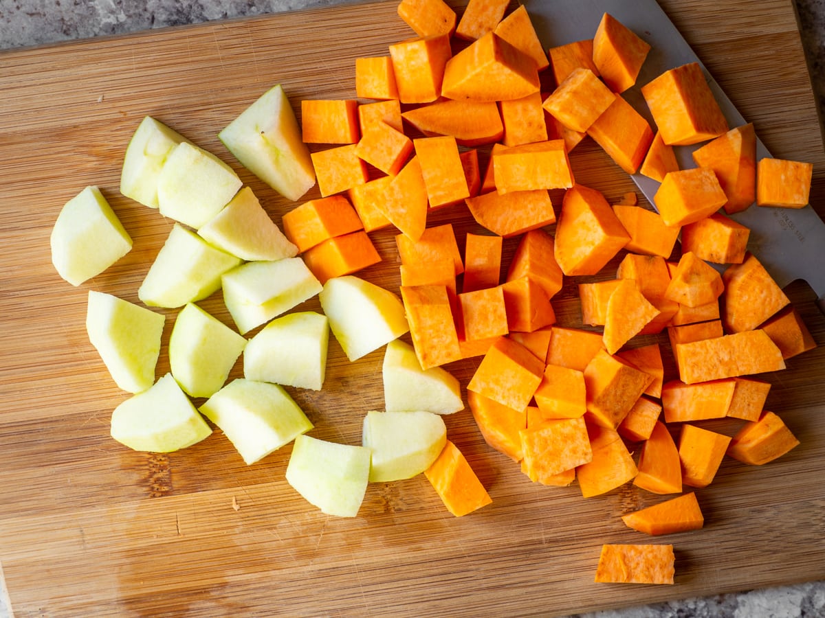 Apples and sweet potatoes diced on a cutting board.