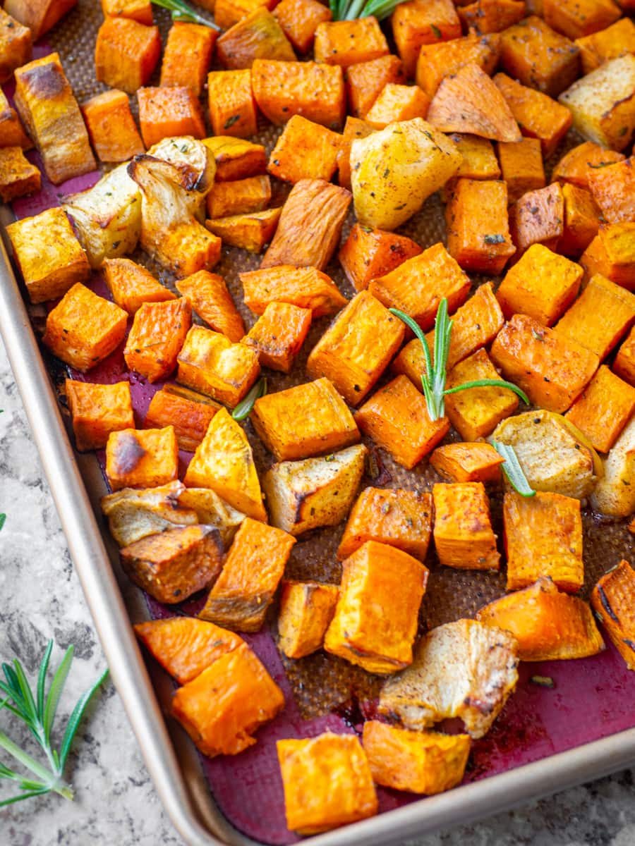 Baked apples and sweet potatoes on a baking sheet.