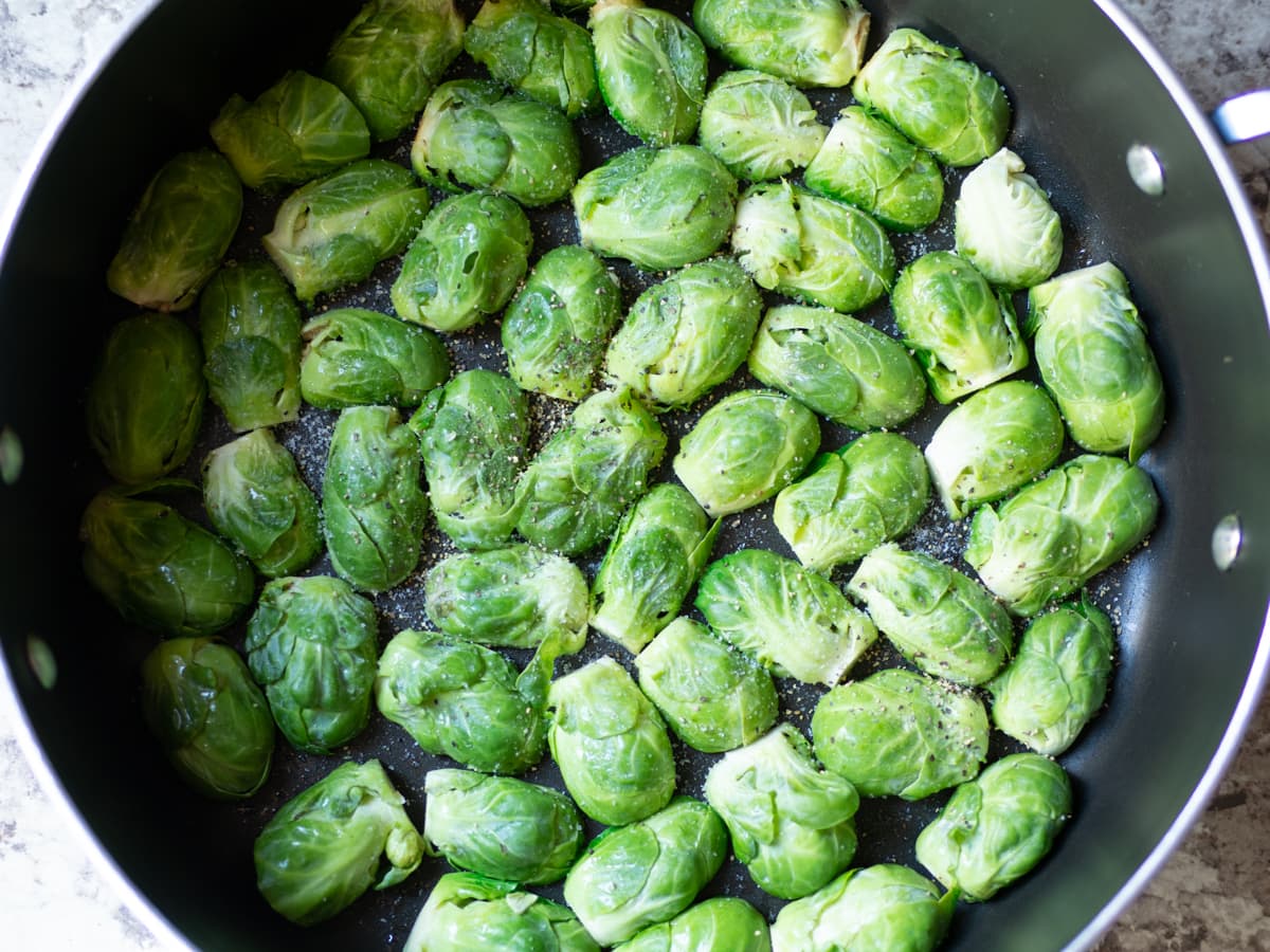 Raw Brussels sprouts added in a single layer to a skillet of heated oil.